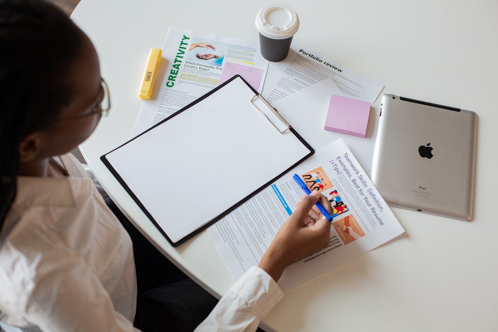 Top view of a woman reviewing various documents with a clipboard on a desk.